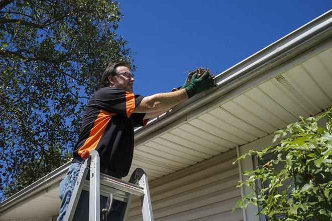 a worker using a ladder to fix a damaged gutter in Buellton